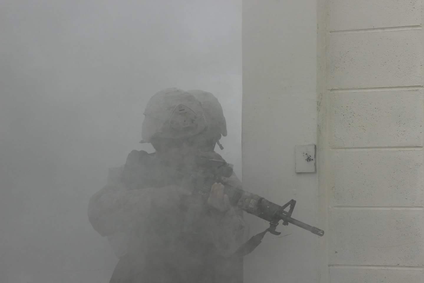 A soldier in the fog holding his rifle.