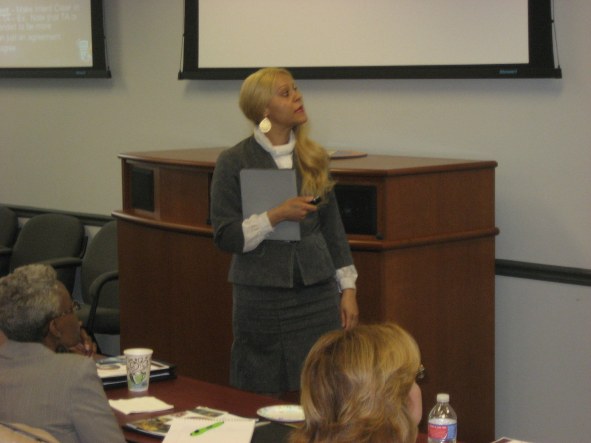 A woman standing in front of a podium holding a book.